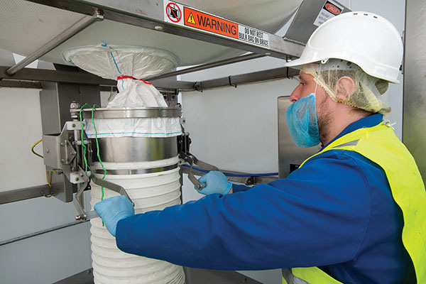 Once the bag spout is secured by a SPOUT-LOCK™ clamp ring, the operator releases the drawstring (red). Constant downward tension is maintained by a TELE-TUBE™ telescoping tube as the bag empties and elongates.
