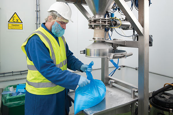Operator ties off and removes filled 10 kg plastic bag for storage.